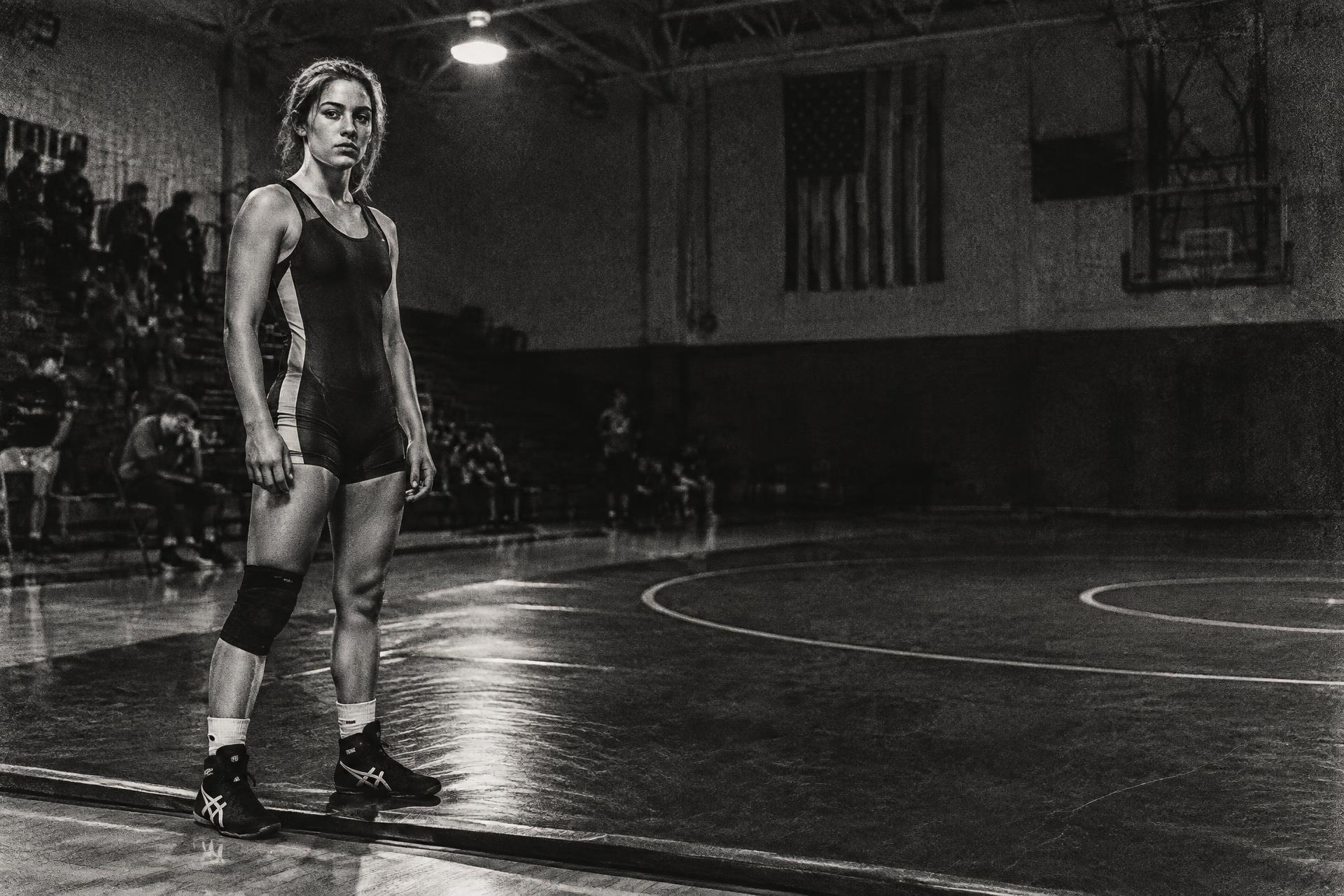 Female wrestler standing alone on a wrestling mat